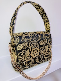 a black and gold handbag with a gold chain